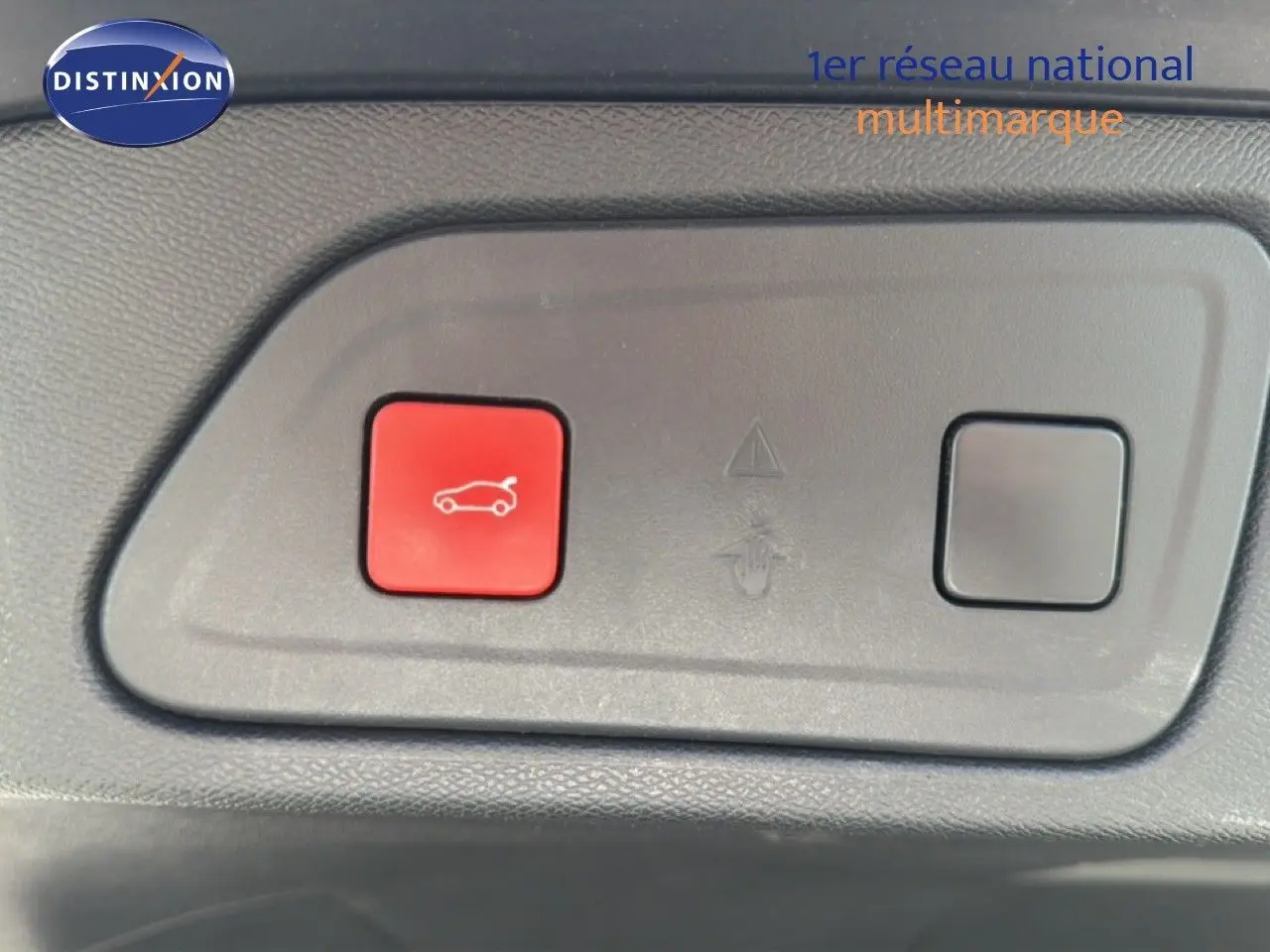 Vue rapprochée du bouton rouge d'ouverture du hayon sur un tableau de bord gris du Citroën C5 Aircross gris acier.