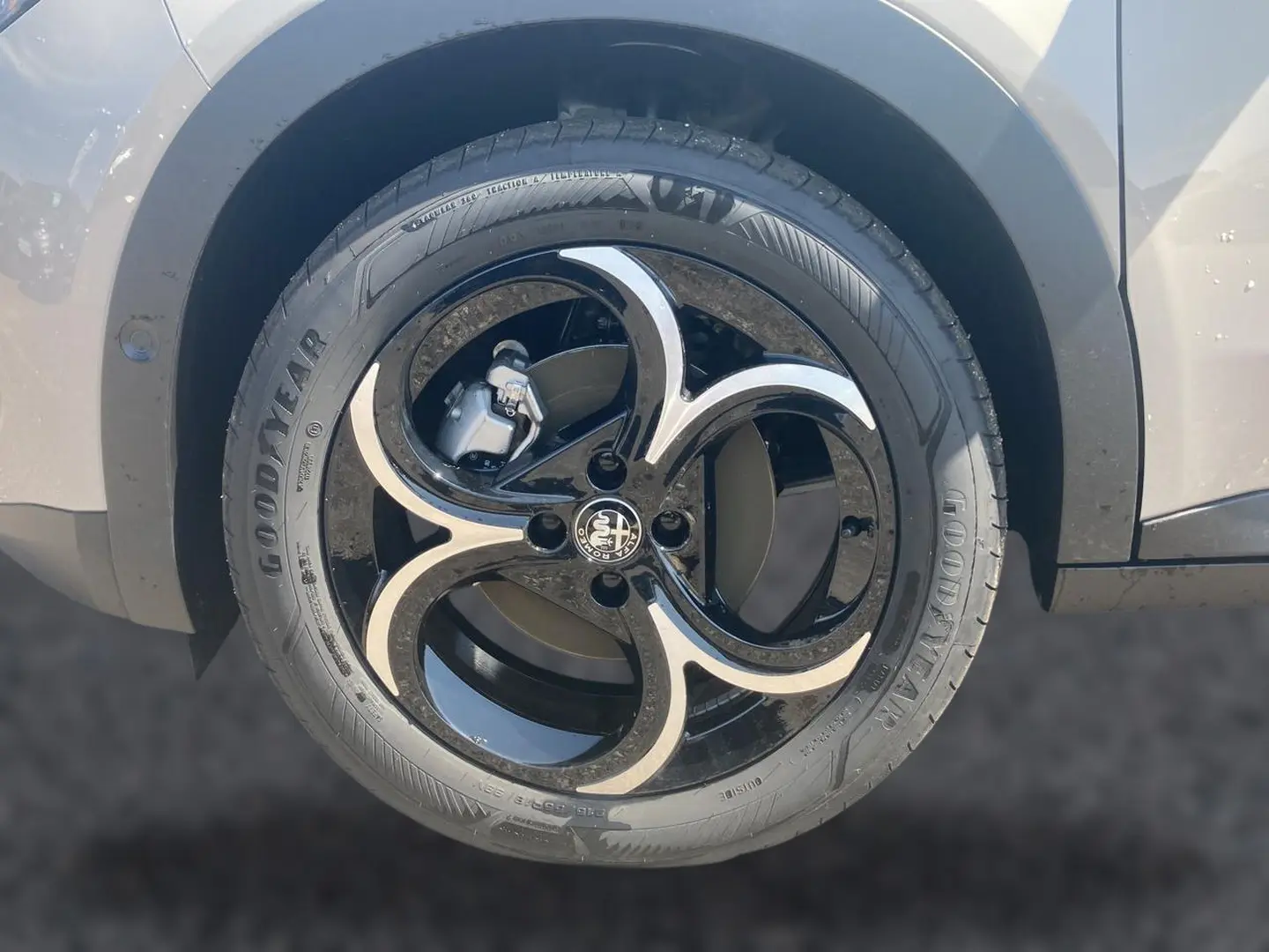 Gros plan sur la jante en alliage noire et ivoire d'une Alfa Romeo Junior 1.2 hybride, côté arrière droit.