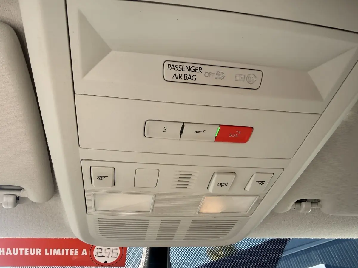 Vue intérieure du plafonnier gris clair du Volkswagen Transporter 2.0 TDi 110 L2H1 Business avec bouton SOS rouge allumé.