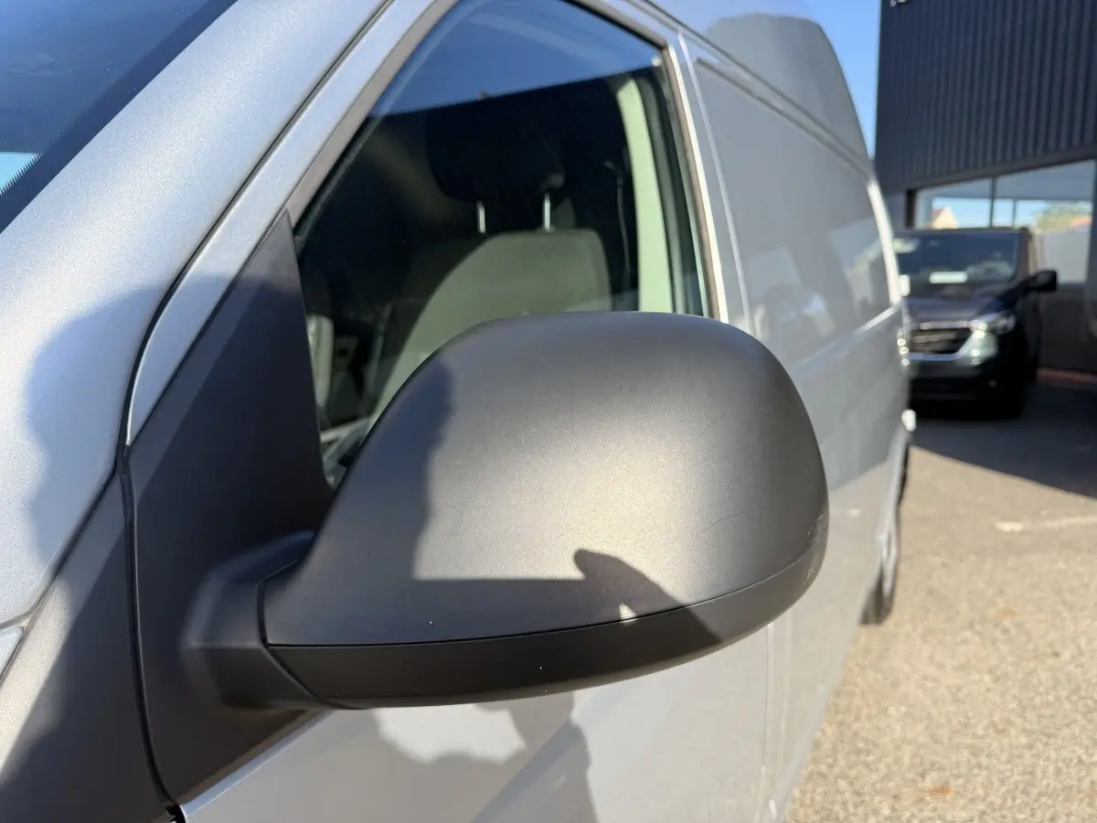 Gros plan sur le rétroviseur côté gauche du Volkswagen Transporter gris clair, vue latérale avant droite.