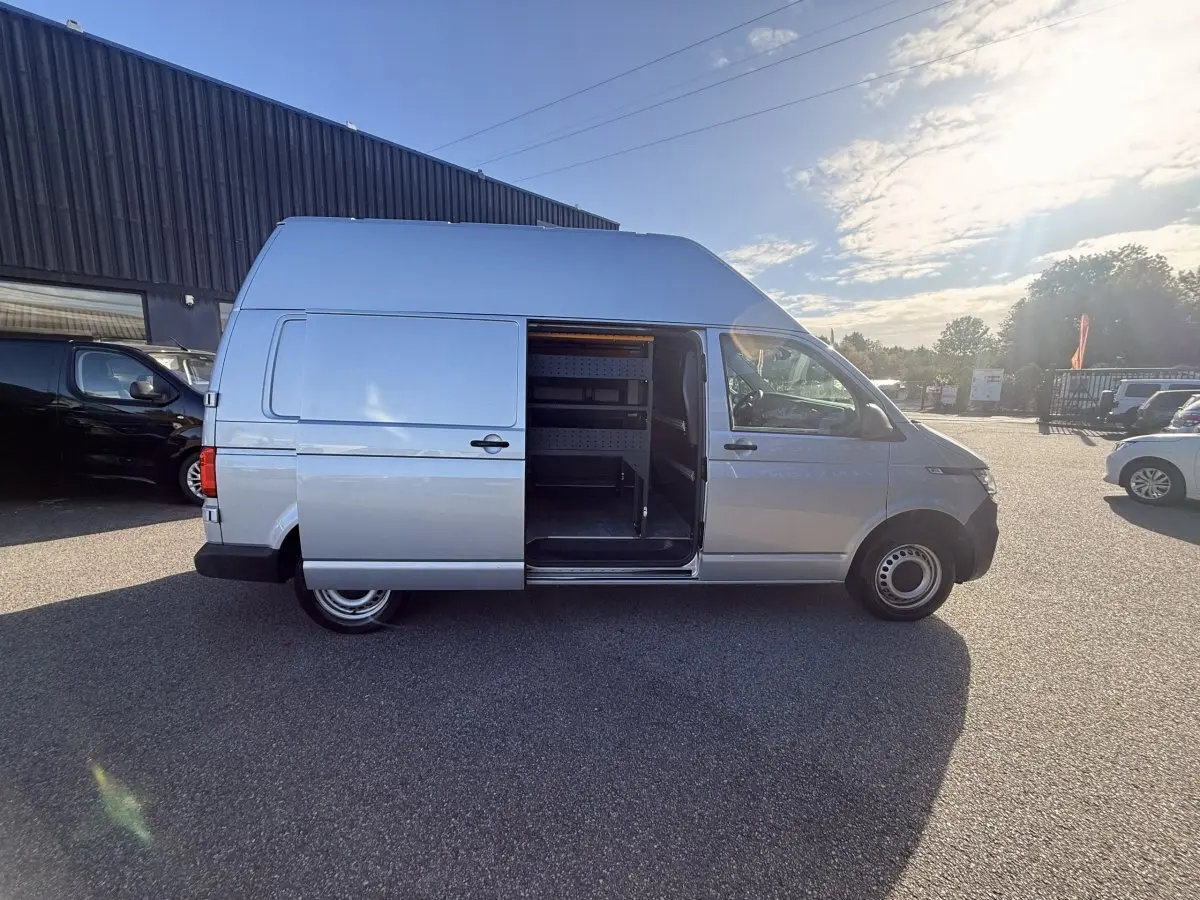 Vue latérale droite d’un Volkswagen Transporter gris clair 2022 avec porte coulissante ouverte montrant l’intérieur aménagé.