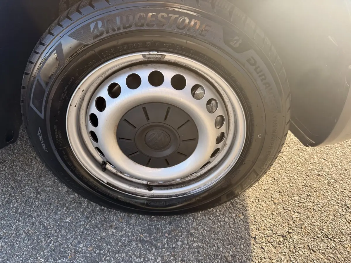 Gros plan sur la roue avant droite du Volkswagen Transporter gris clair avec jante acier et pneu Bridgestone.