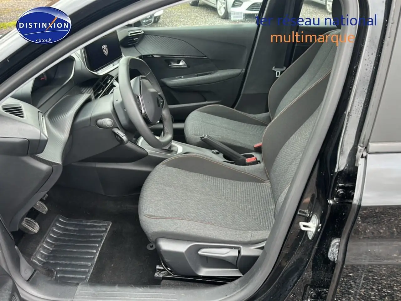 Vue intérieure côté conducteur de la Peugeot 208 noire 1.2 100 style avec sièges gris et tableau de bord moderne.