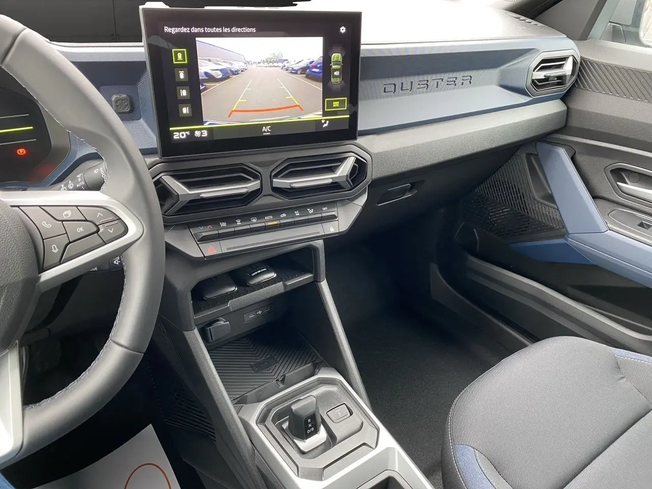 Vue intérieure côté conducteur du Dacia Duster 2025 gris schiste, avec écran tactile central et tableau de bord moderne.