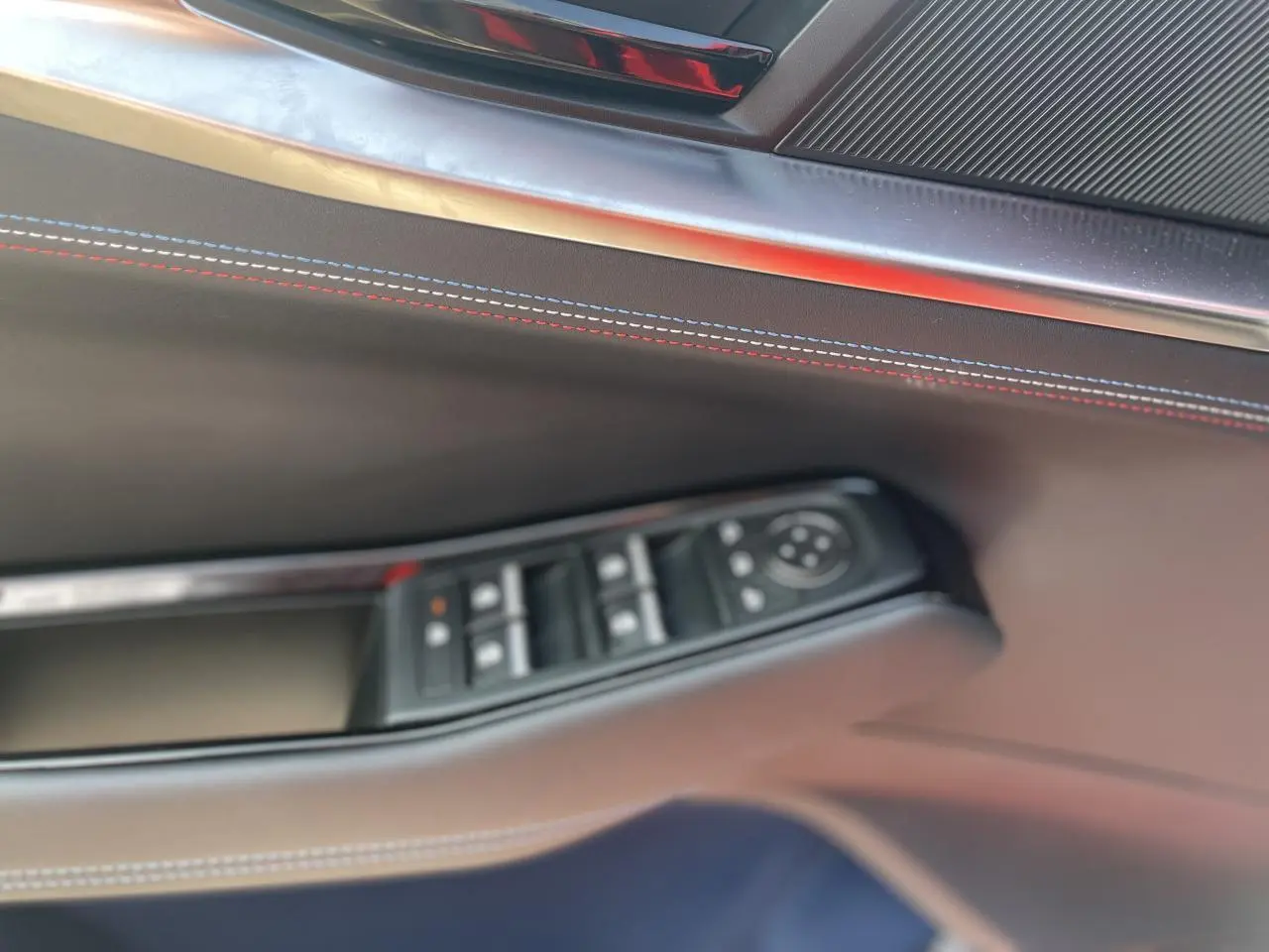 Détail de la porte côté gauche de la Renault Rafale 2025 avec surpiqûres tricolores et commandes de vitres.