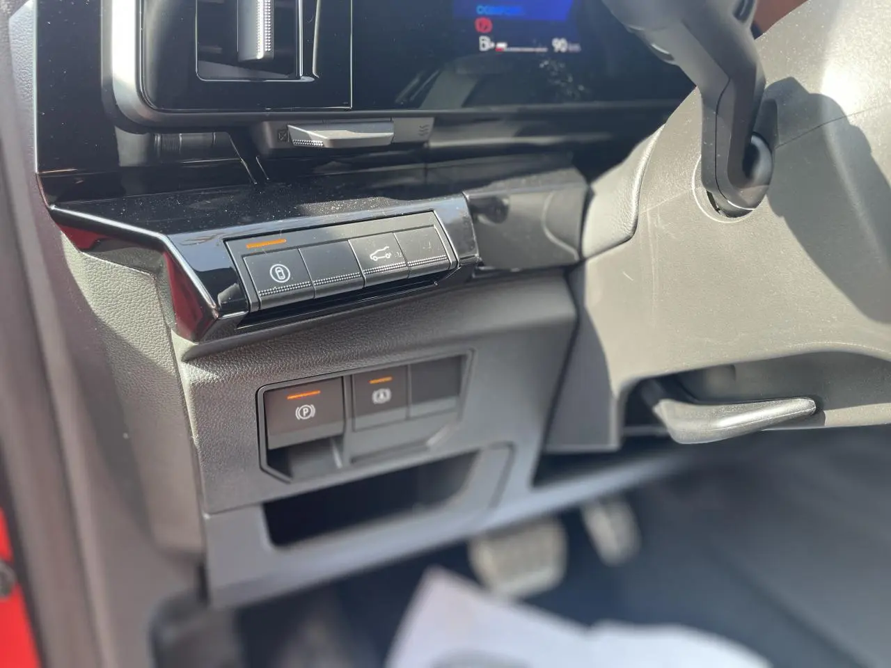 Détail intérieur côté gauche du tableau de bord du Renault Rafale 2025 rouge, avec commandes électroniques et pédalier visible.