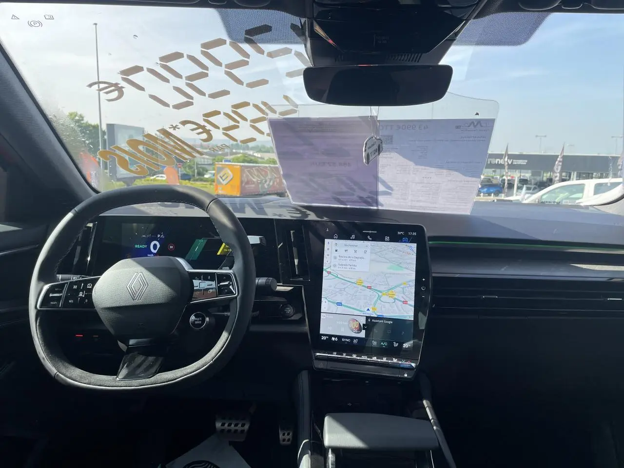 Vue intérieure avant du Renault Rafale 2025, volant Alcantara avec logo, écran tactile vertical affichant la navigation.
