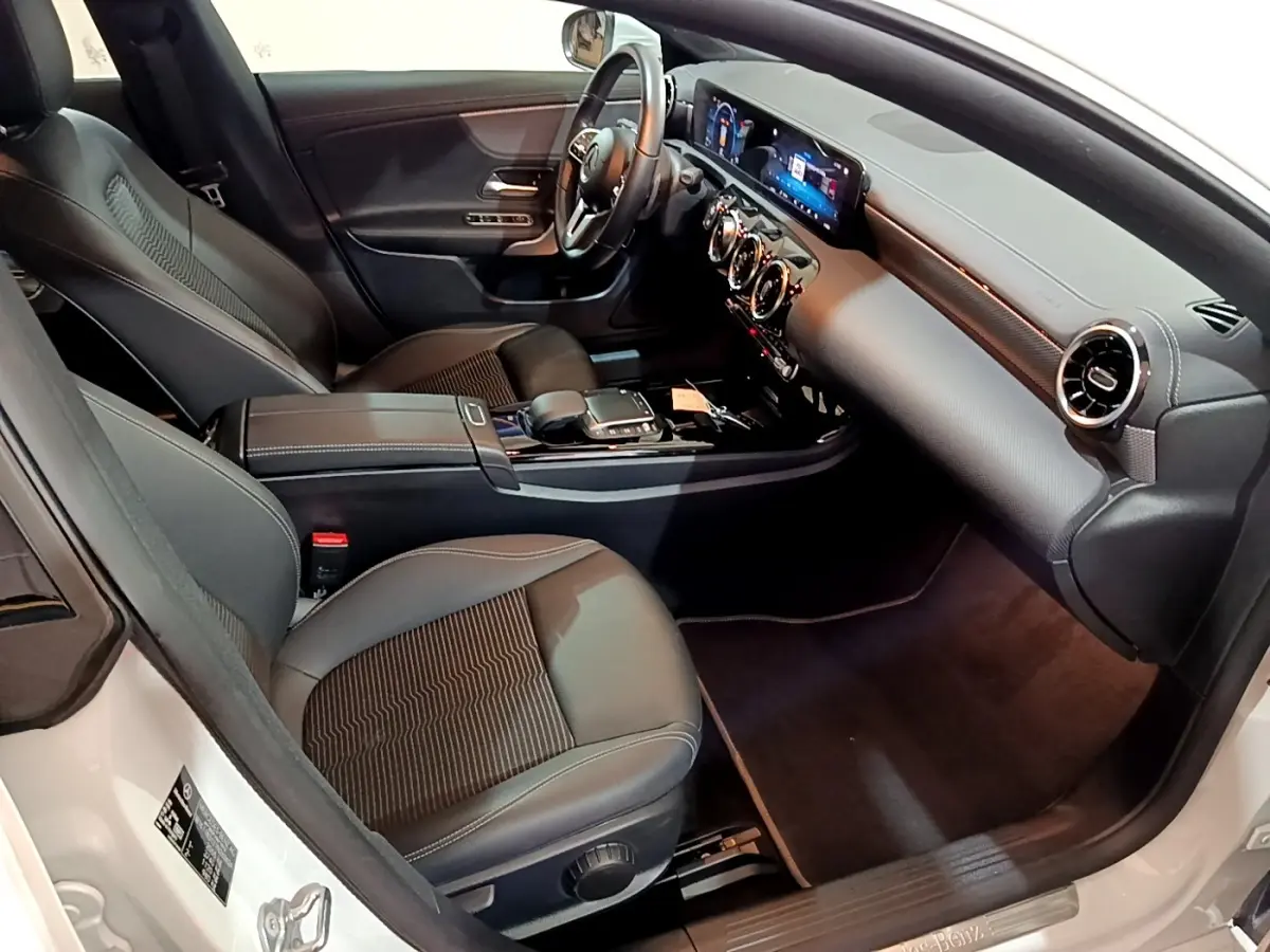 Vue intérieure côté conducteur de la Mercedes CLA 200 d Business Line blanche, tableau de bord digital et sièges noirs.