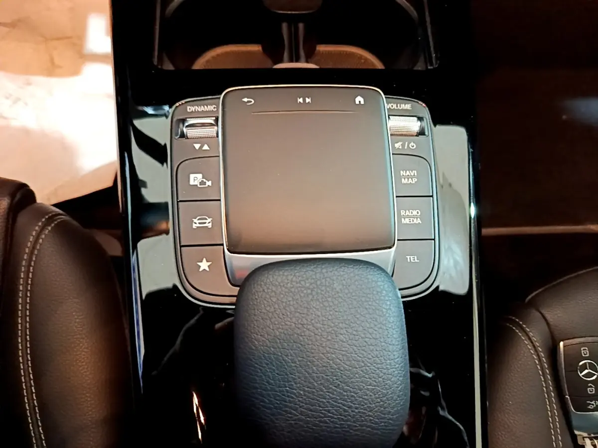 Vue rapprochée du pavé tactile central noir brillant et du levier de vitesse en cuir dans l’habitacle d’une Mercedes CLA 200 d blanche.
