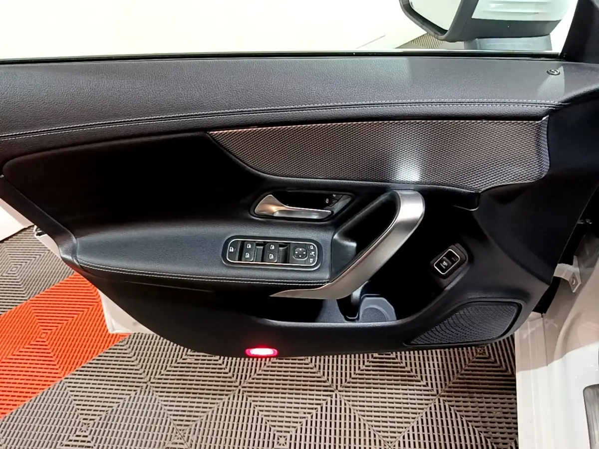 Vue intérieure du panneau de porte avant gauche noir avec commandes électriques sur Mercedes CLA 200 d blanc.