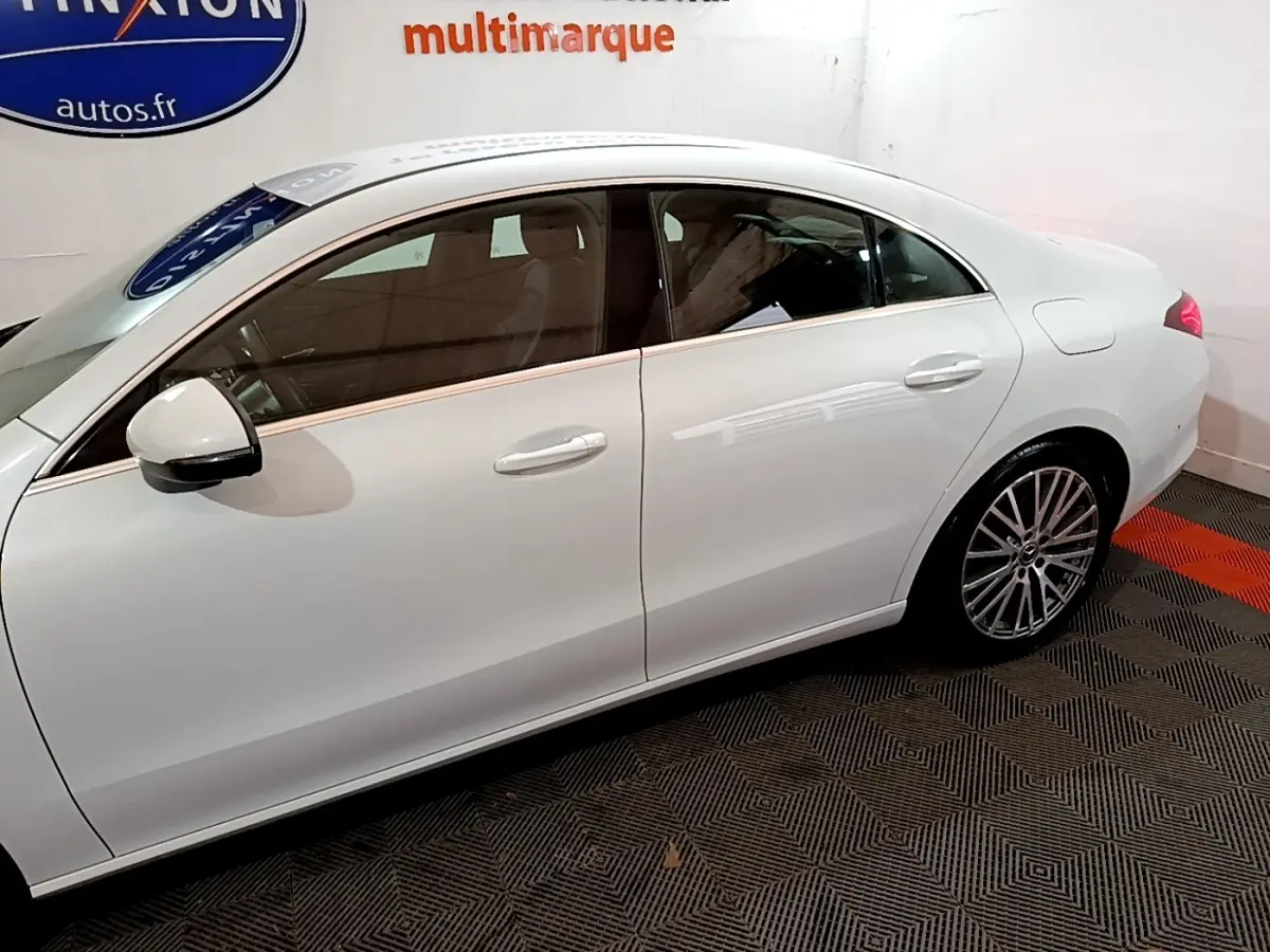 Vue latérale côté gauche d'une Mercedes CLA 200 d Business Line blanche, avec jantes alliage et rétroviseur blanc.