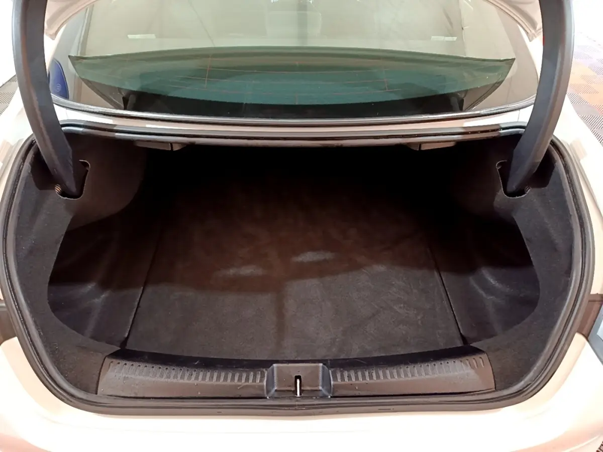 Coffre ouvert vu de dessus d'une Mercedes CLA 200 d Business Line blanche, espace de chargement vide et propre.