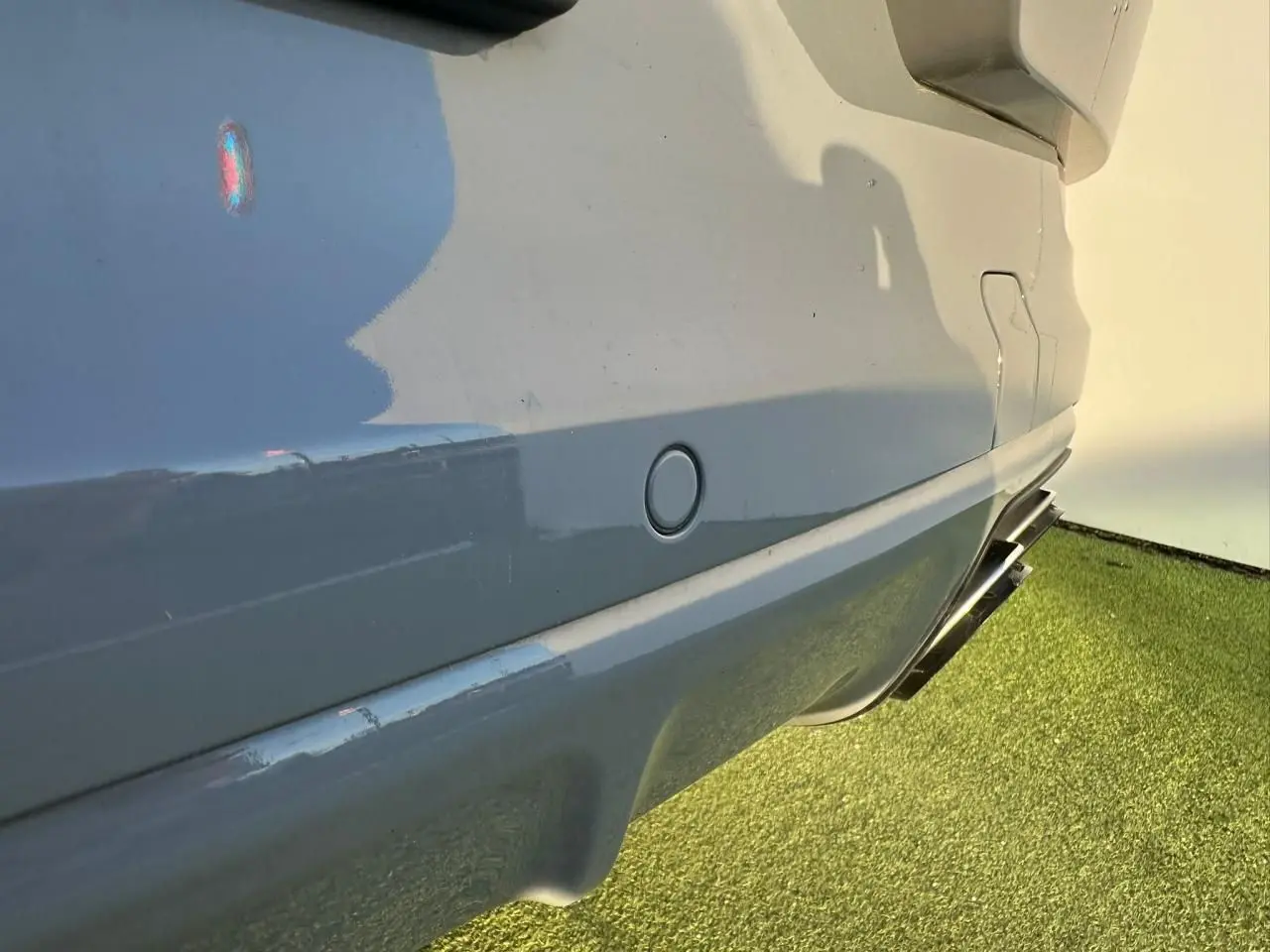 Gros plan sur le côté droit arrière gris arctique du Porsche Cayenne 2024, avec sortie d’échappement double visible.