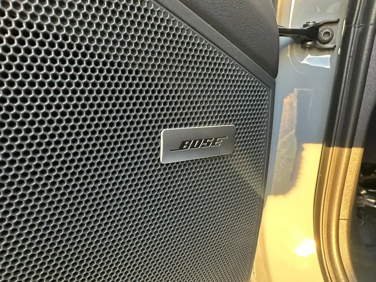 Gros plan sur l’enceinte Bose intégrée à la porte côté droit d’un Porsche Cayenne Coupé gris arctique 2024.
