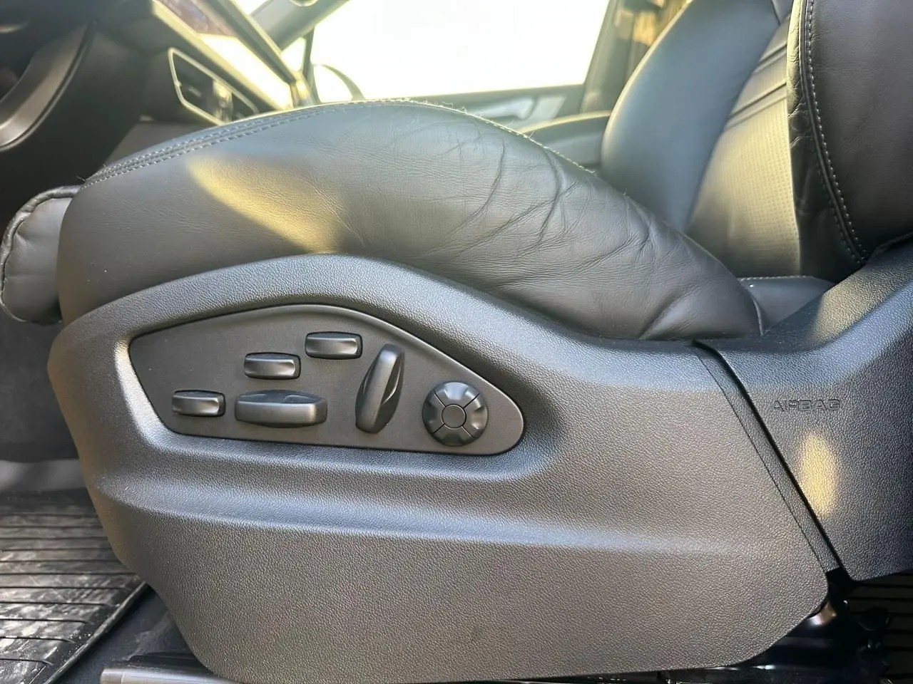Gros plan sur les commandes électriques du siège conducteur en cuir noir du Porsche Cayenne Coupé gris arctique 2024.
