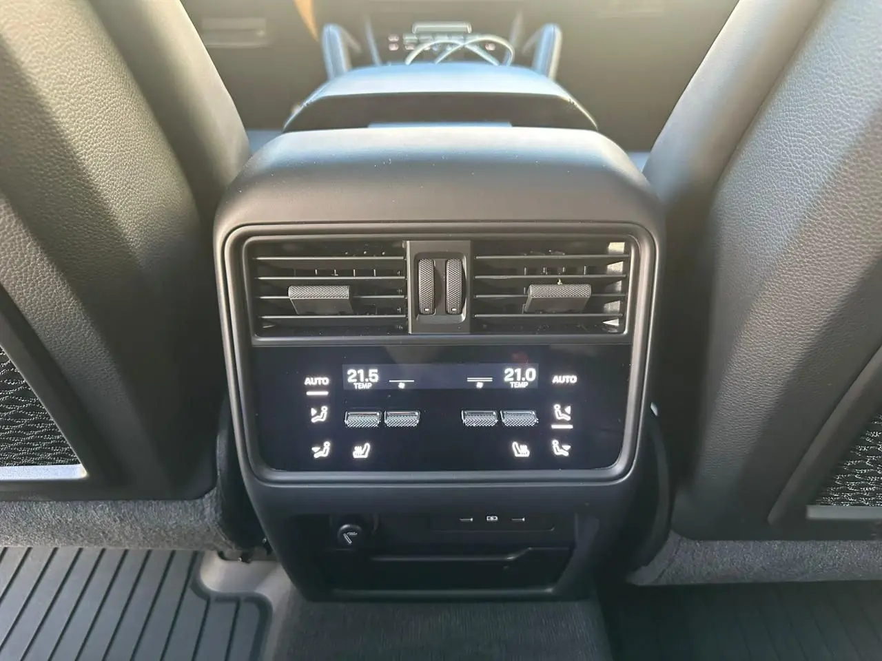 Détail de la console arrière du Porsche Cayenne 2024 en gris arctique, montrant les commandes de climatisation et les aérateurs.