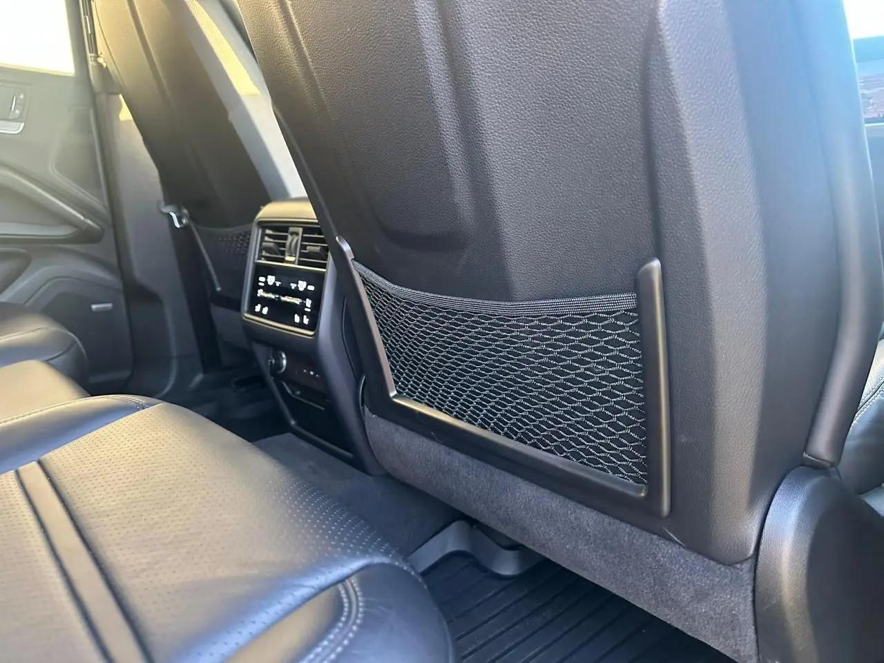 Vue intérieure arrière du Porsche Cayenne 2024, montrant les sièges en cuir noir et la console centrale avec commandes climatisation.