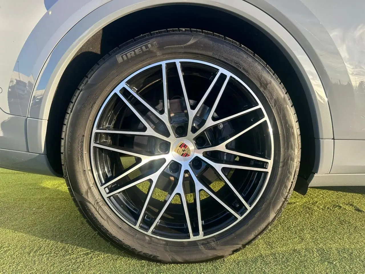 Gros plan sur la roue avant droite du Porsche Cayenne 2024 gris arctique, avec jante alliage noire et argentée distinctive.