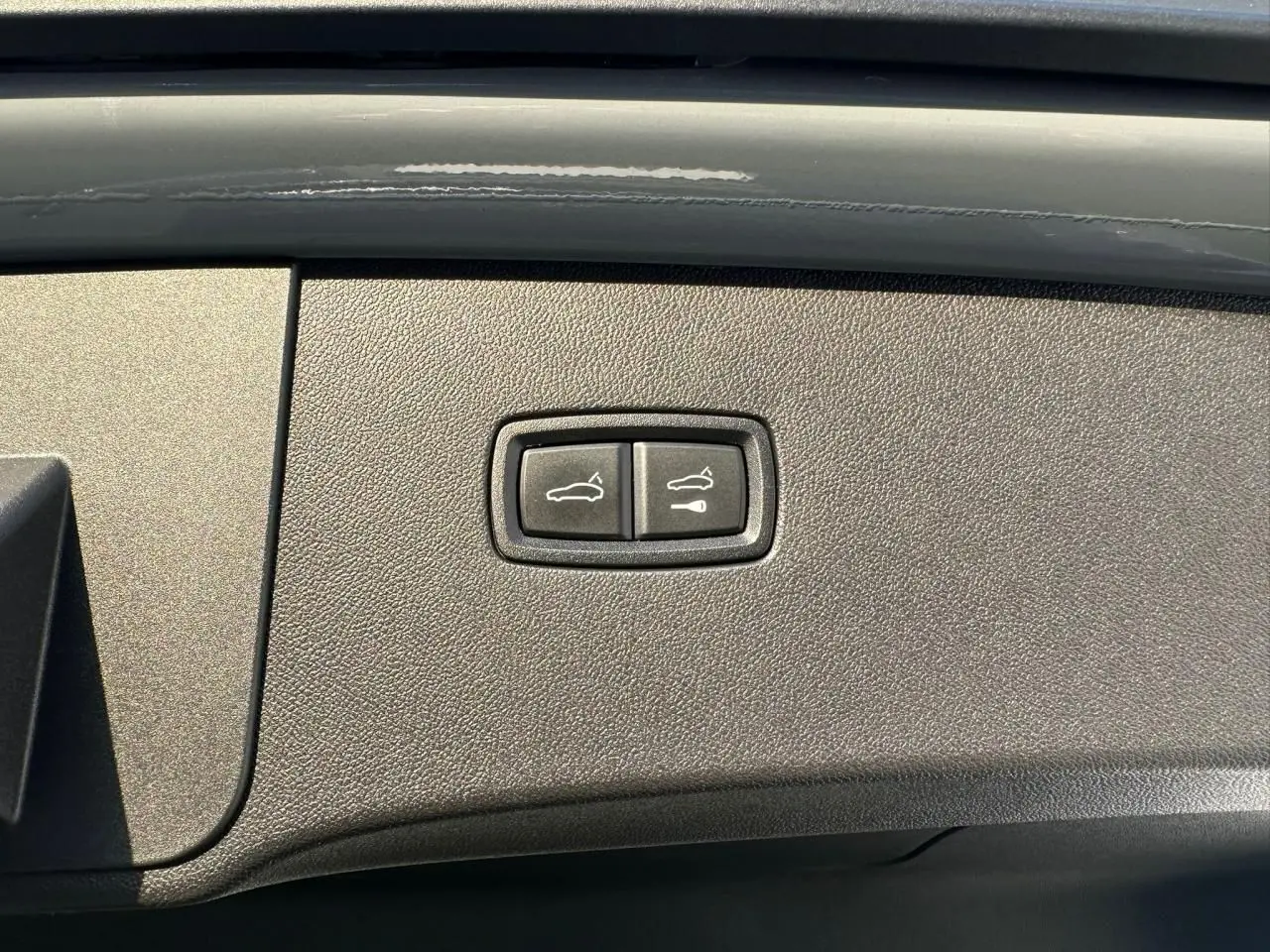 Gros plan sur les boutons d'ouverture du coffre et du hayon du Porsche Cayenne Coupé 2024 en gris arctique.