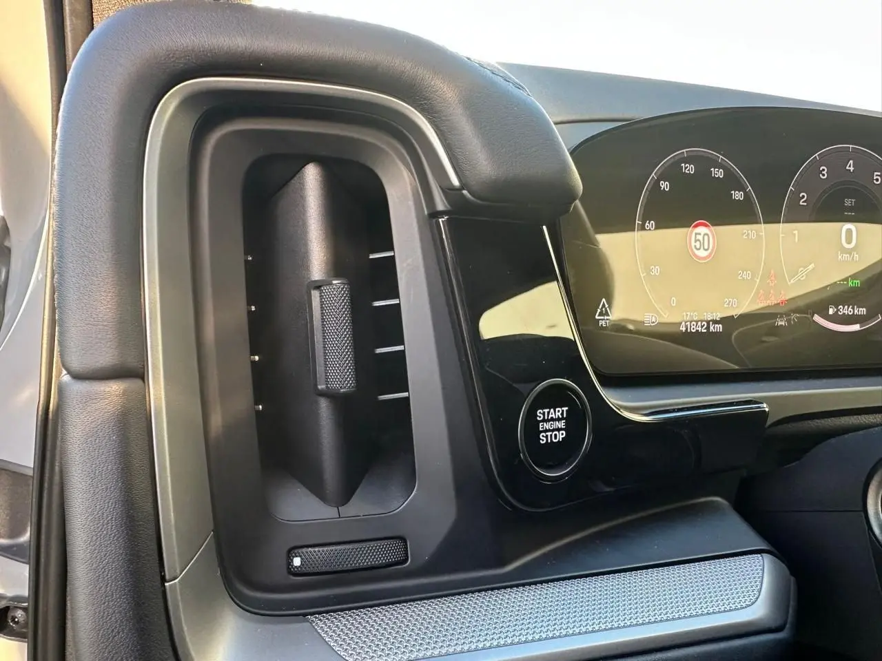 Détail intérieur du tableau de bord côté gauche du Porsche Cayenne 2024, avec bouton Start Engine Stop et écran digital.