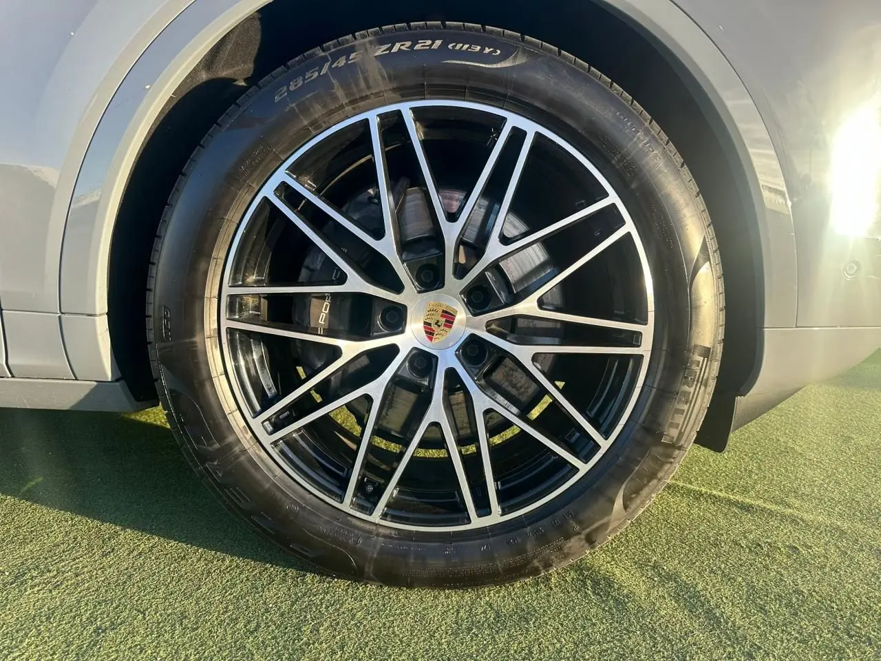 Gros plan sur la roue avant droite du Porsche Cayenne 2024 gris arctique, mettant en valeur la jante alliage noire et argentée.