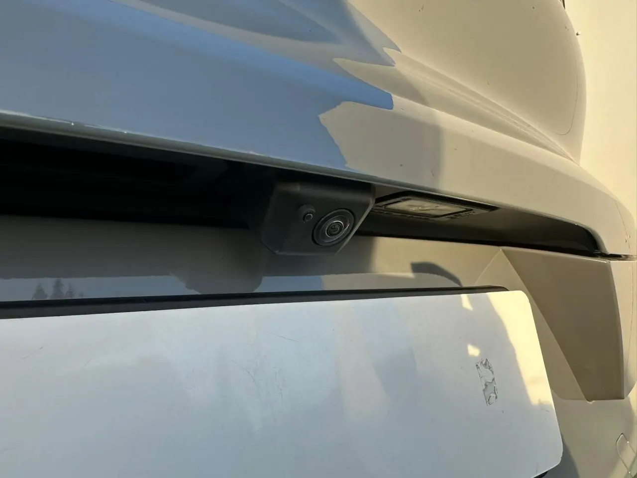 Gros plan sur la caméra de recul intégrée au pare-chocs arrière du Porsche Cayenne Coupé gris arctique 2024.