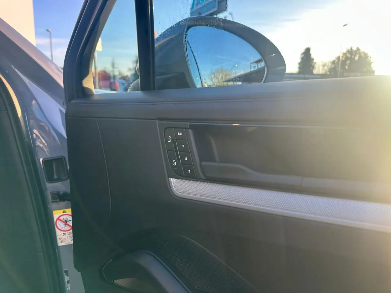 Détail de la porte avant gauche du Porsche Cayenne 2024 gris arctique, avec commandes de verrouillage et miroir extérieur.