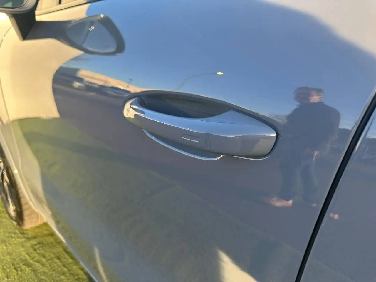 Poignée de porte côté gauche d'un Porsche Cayenne 2024 gris arctique, reflet net sur la carrosserie lisse.