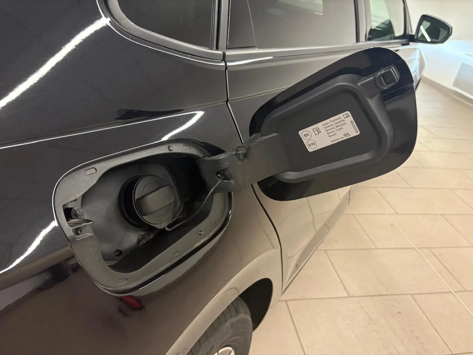 Vue rapprochée du côté gauche arrière d'une Volkswagen Polo noire intense avec trappe à carburant ouverte.