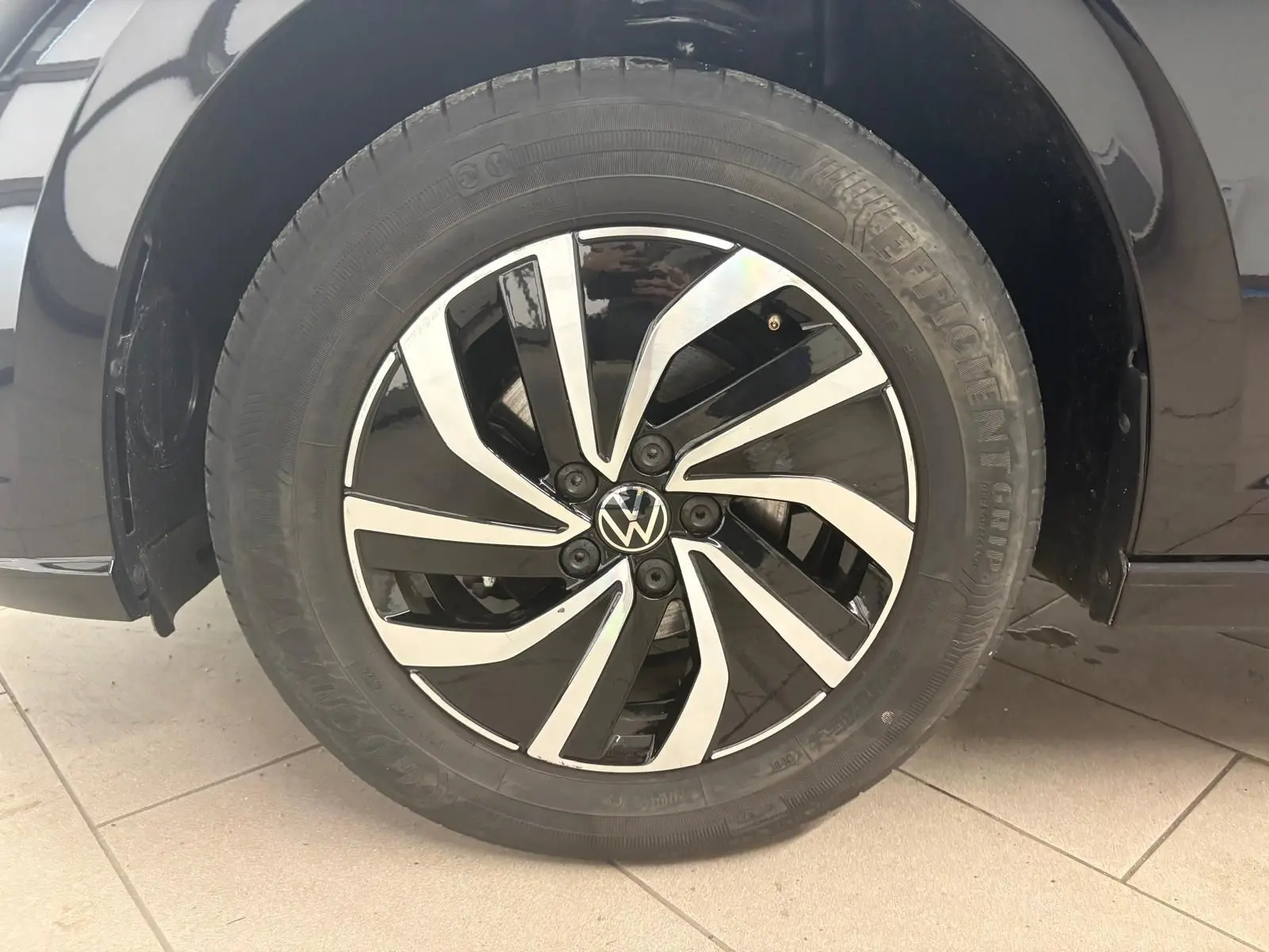 Gros plan sur la jante alliage bicolore noire et argentée d'une Volkswagen Polo noire intense, côté droit.