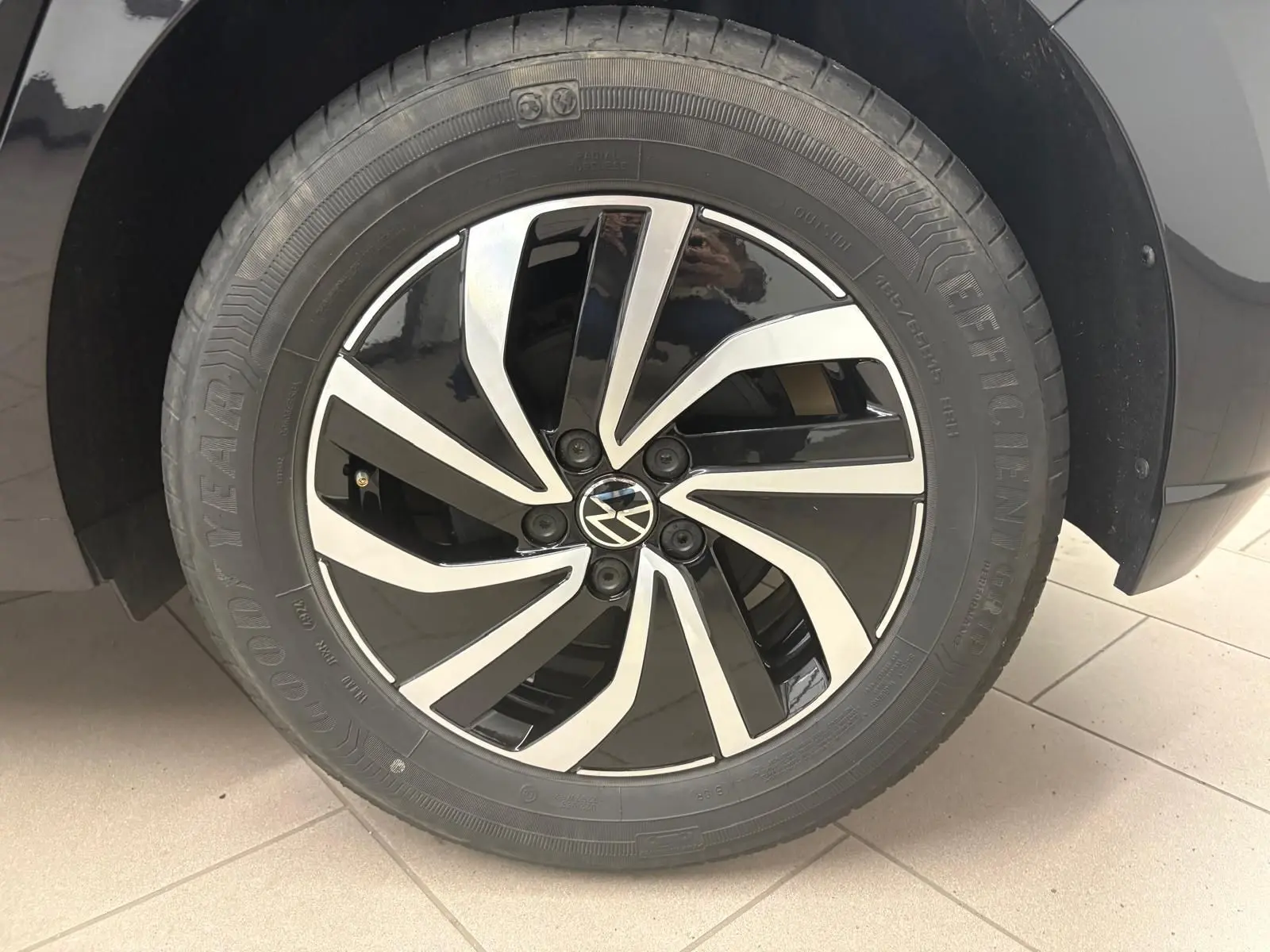 Gros plan sur la jante alliage 15'' bicolore noir et argent avec logo Volkswagen sur une Polo noir intense.