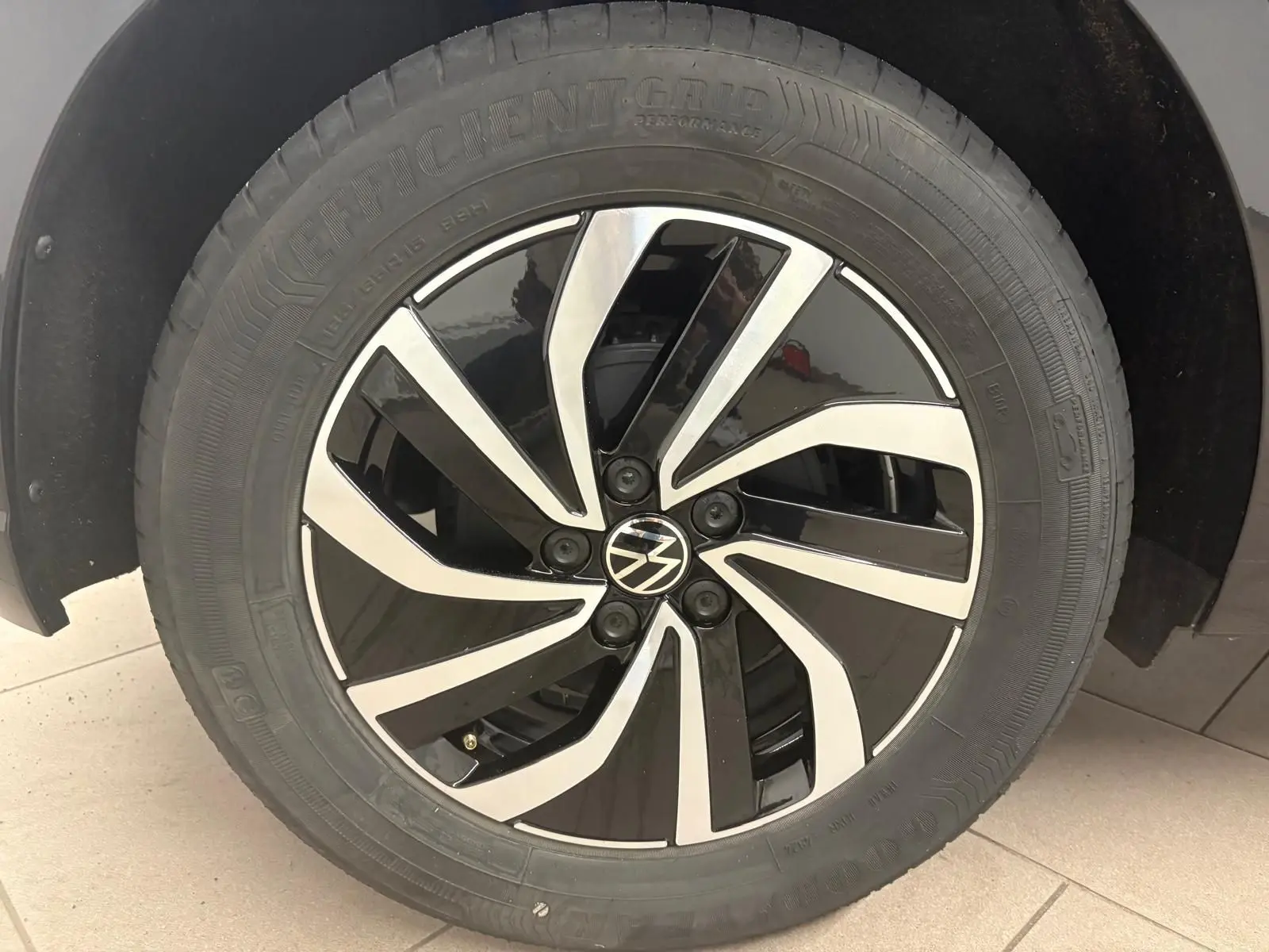 Gros plan sur la jante alliage bicolore noire et argentée avec logo Volkswagen au centre, montée sur un pneu Goodyear.