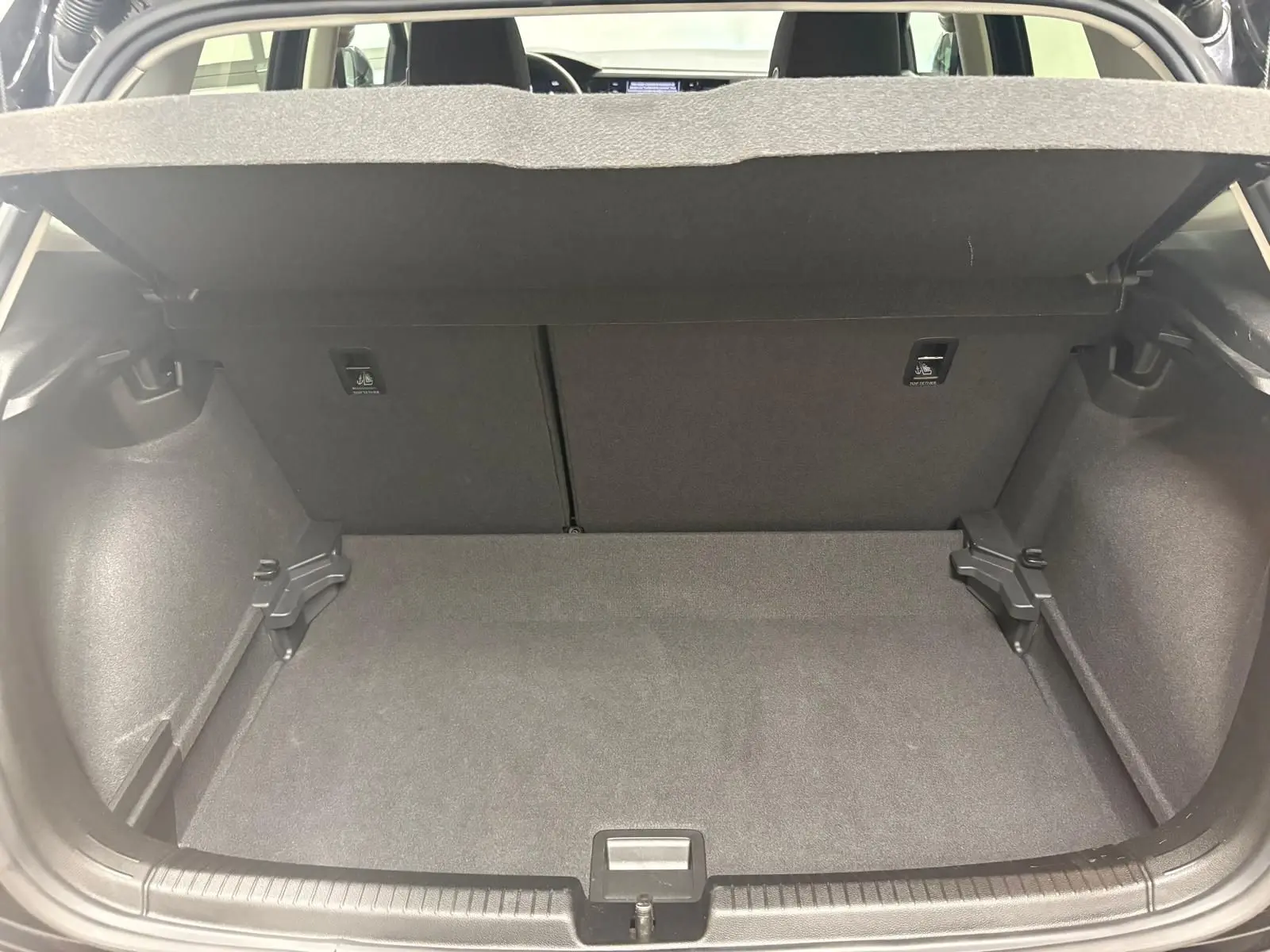 Coffre ouvert de Volkswagen Polo noir intense 2025, vue intérieure montrant l'espace de chargement vide et tapis gris.