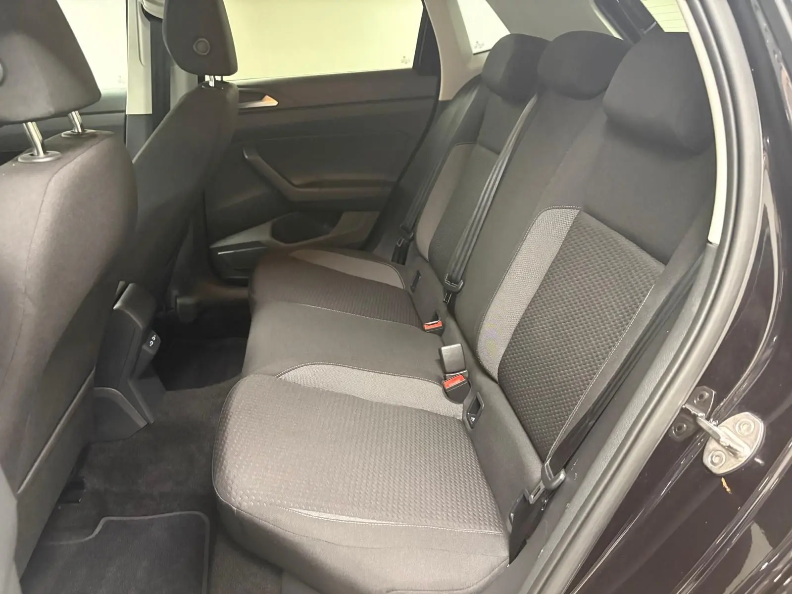 Vue intérieure côté droit de la banquette arrière noire et grise de la Volkswagen Polo 2025 avec ceintures de sécurité visibles.
