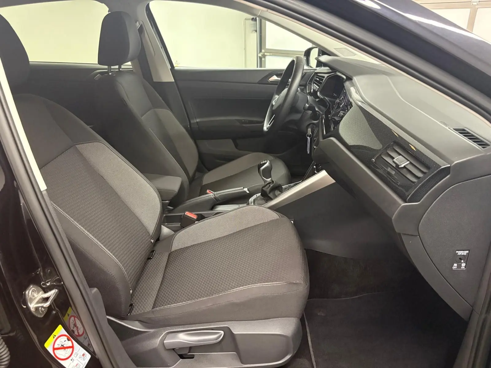 Intérieur avant de la Volkswagen Polo noir intense, vue côté conducteur montrant sièges et tableau de bord moderne.