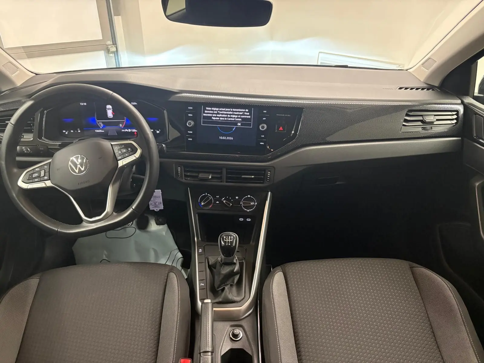 Vue intérieure avant de la Volkswagen Polo noire intense 2025, volant cuir multifonctions et tableau de bord digital.