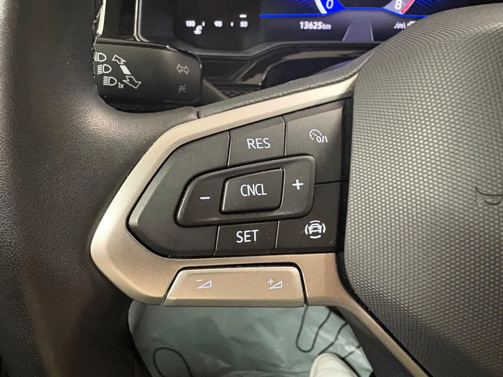 Gros plan sur les commandes du volant cuir de la Volkswagen Polo 2025, boutons de régulateur de vitesse visibles.