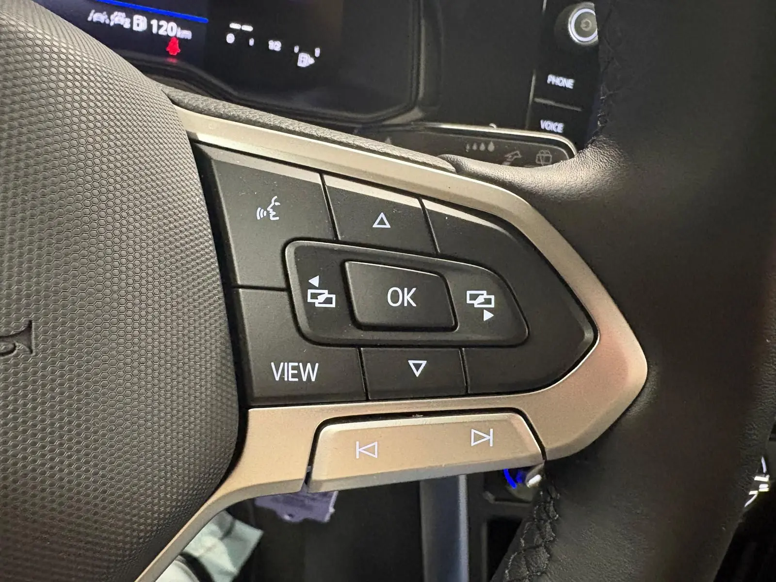 Gros plan sur les commandes multifonctions du volant cuir d'une Volkswagen Polo noire intense, avec écran digital en arrière-plan.