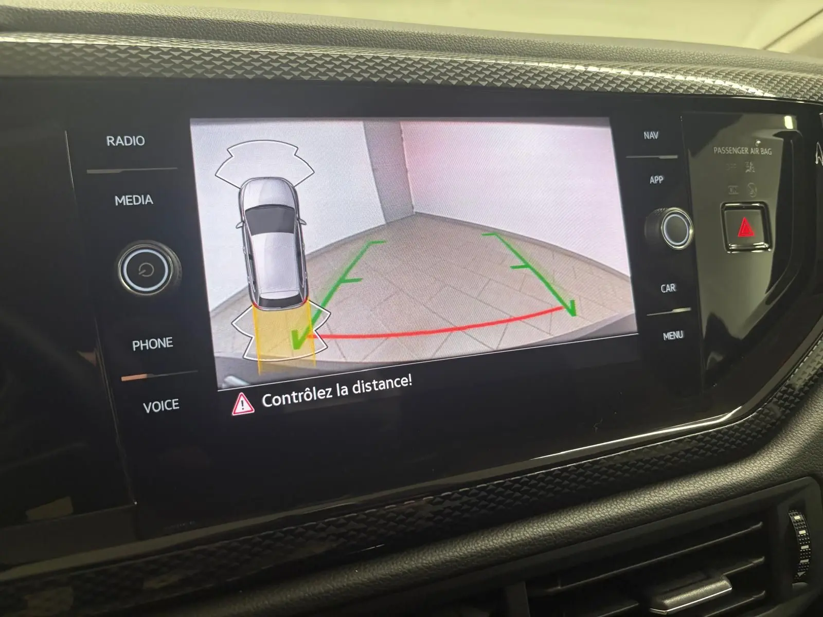 Écran tactile intérieur affichant la caméra de recul avec vue aérienne du véhicule gris et lignes de guidage colorées.