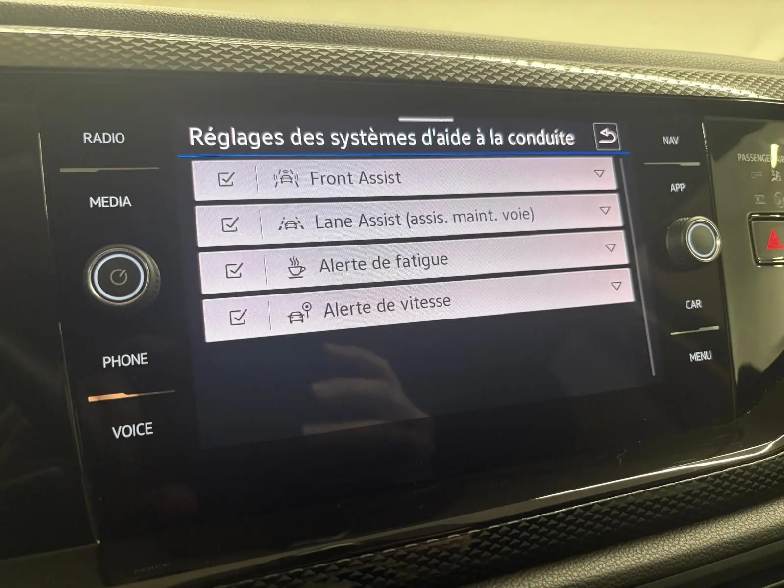 Écran tactile intérieur affichant les réglages d'aide à la conduite dans une Volkswagen Polo noire.