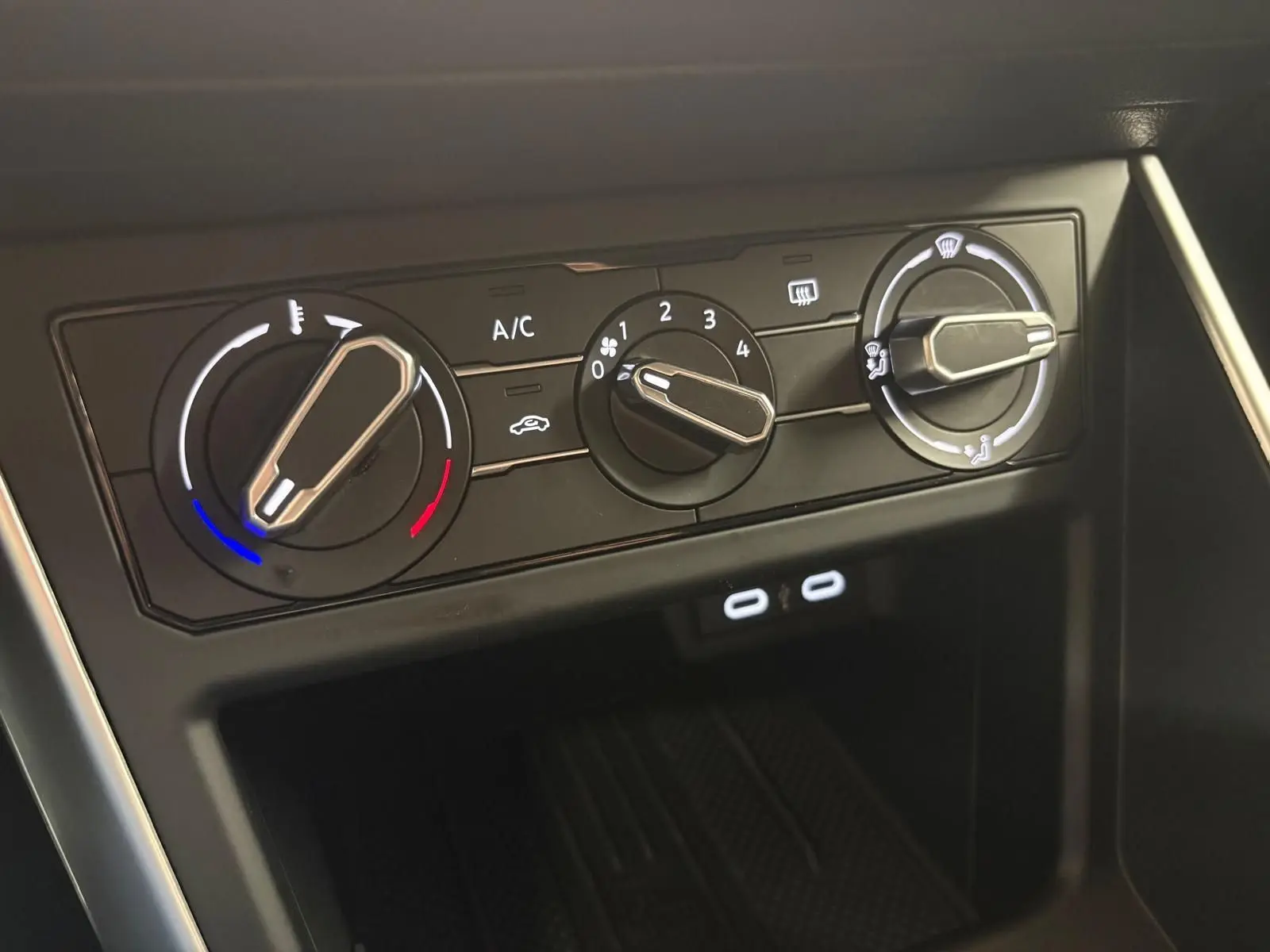 Gros plan sur les commandes de climatisation manuelle noire avec trois molettes dans une Volkswagen Polo 2025.