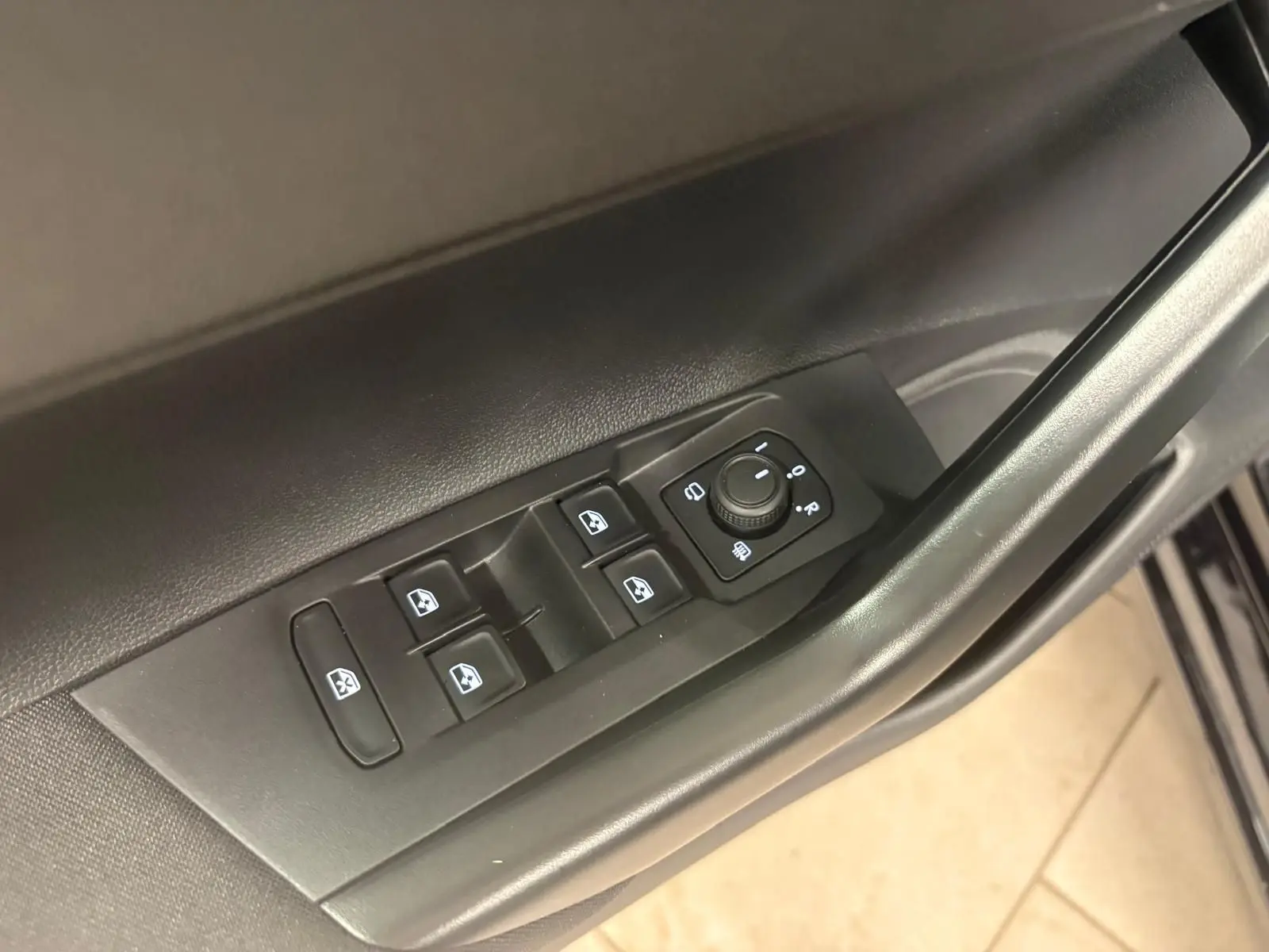 Vue rapprochée des commandes de lève-vitres et réglage des rétroviseurs sur la porte côté conducteur d'une Volkswagen Polo noire.