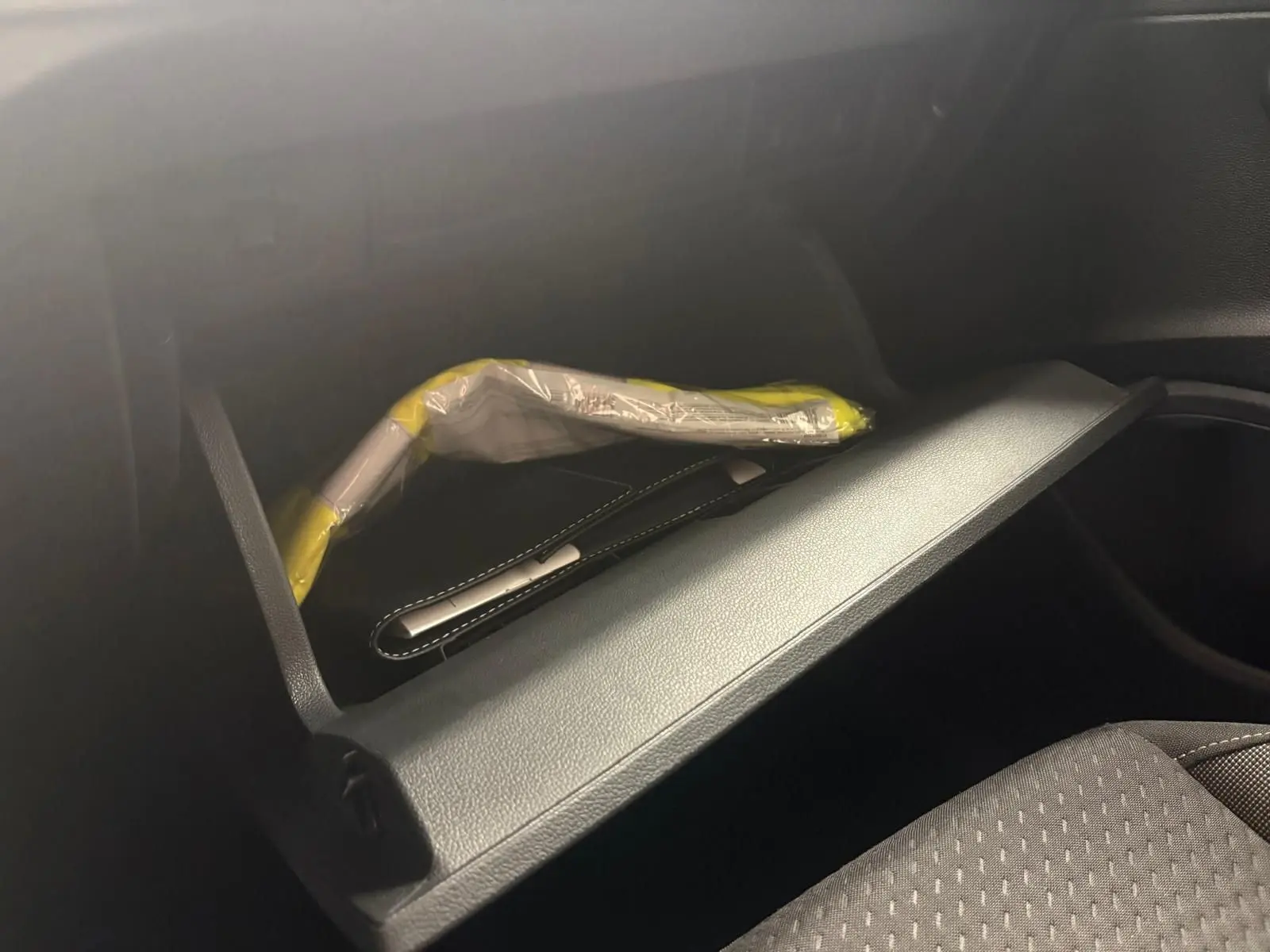 Vue intérieure du vide-poche passager de la Volkswagen Polo 2025 noir intense avec notice emballée visible.