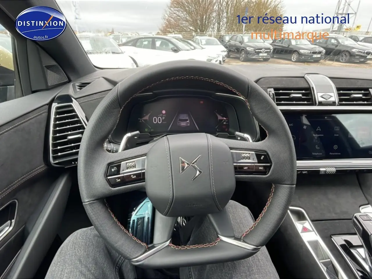 Vue intérieure centrée sur le volant cuir DS du DS7 2026, avec tableau de bord numérique et écran tactile visible.