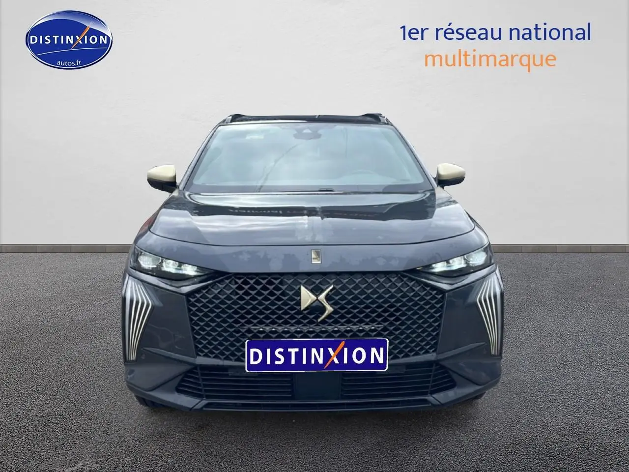 Vue avant d'un DS7 gris titane avec calandre hexagonale et feux LED verticaux distinctifs allumés.