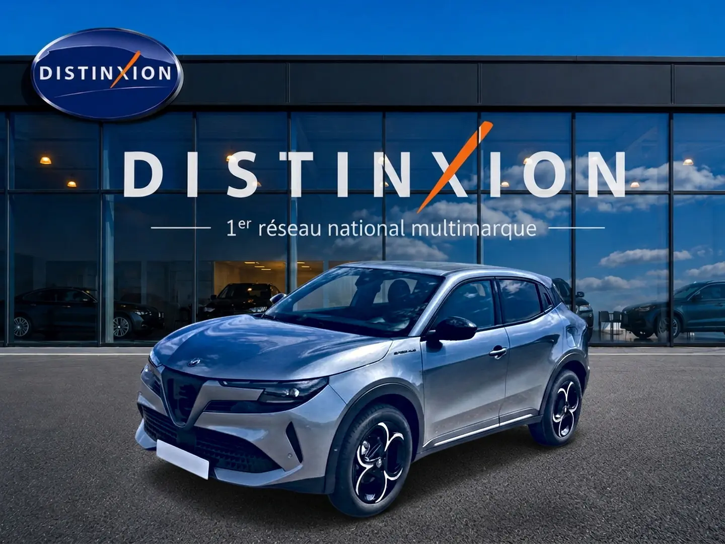 Alfa Romeo Junior 1.2 hybride gris en 3/4 avant droit, avec jantes alliage et vitres arrière teintées, devant showroom Distinxion.