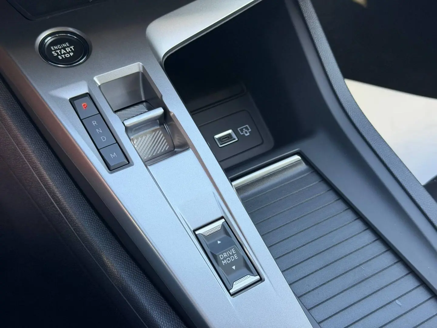 Gros plan sur la console centrale argentée de la Peugeot 308 Hybrid avec levier de boîte auto et bouton Drive Mode.