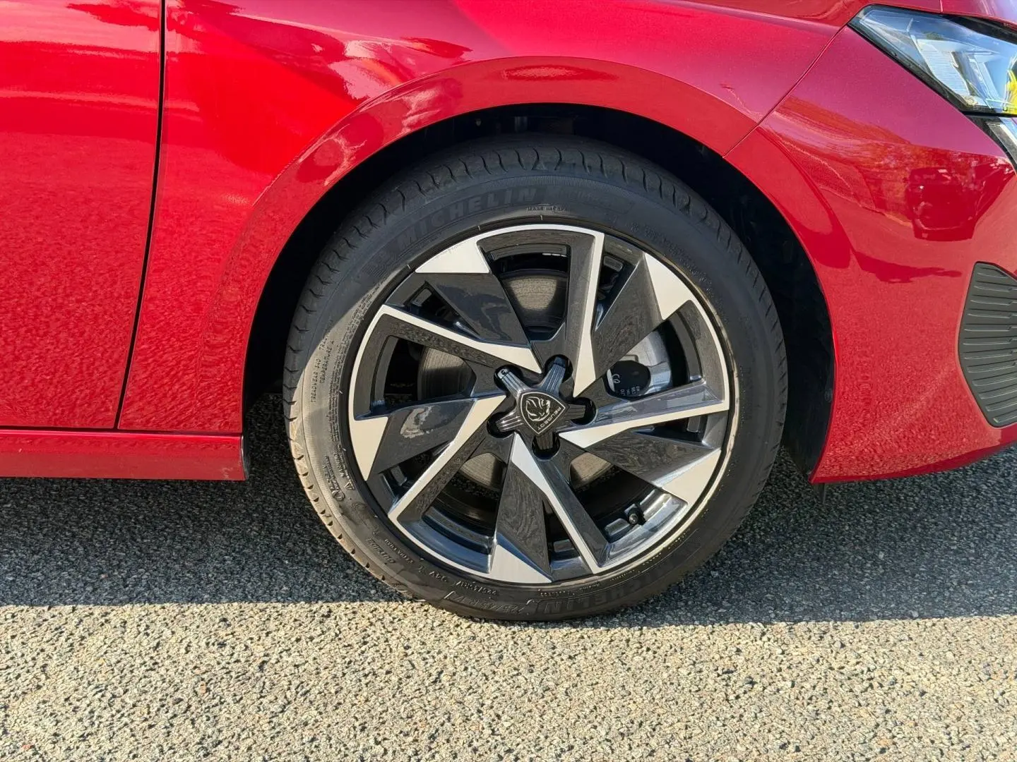 Gros plan sur la roue avant gauche de la Peugeot 308 rouge Elixir avec jante alliage au design moderne.