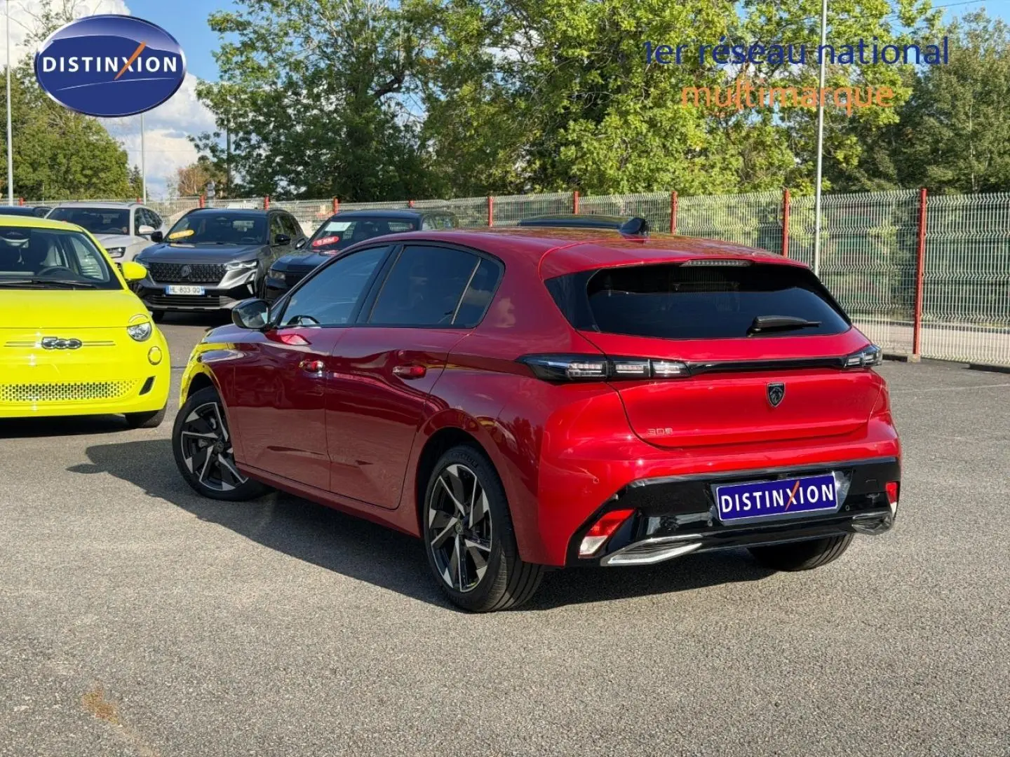 Vue 3/4 arrière droite d'une Peugeot 308 rouge Elixir avec jantes alliage et vitres arrière surteintées.
