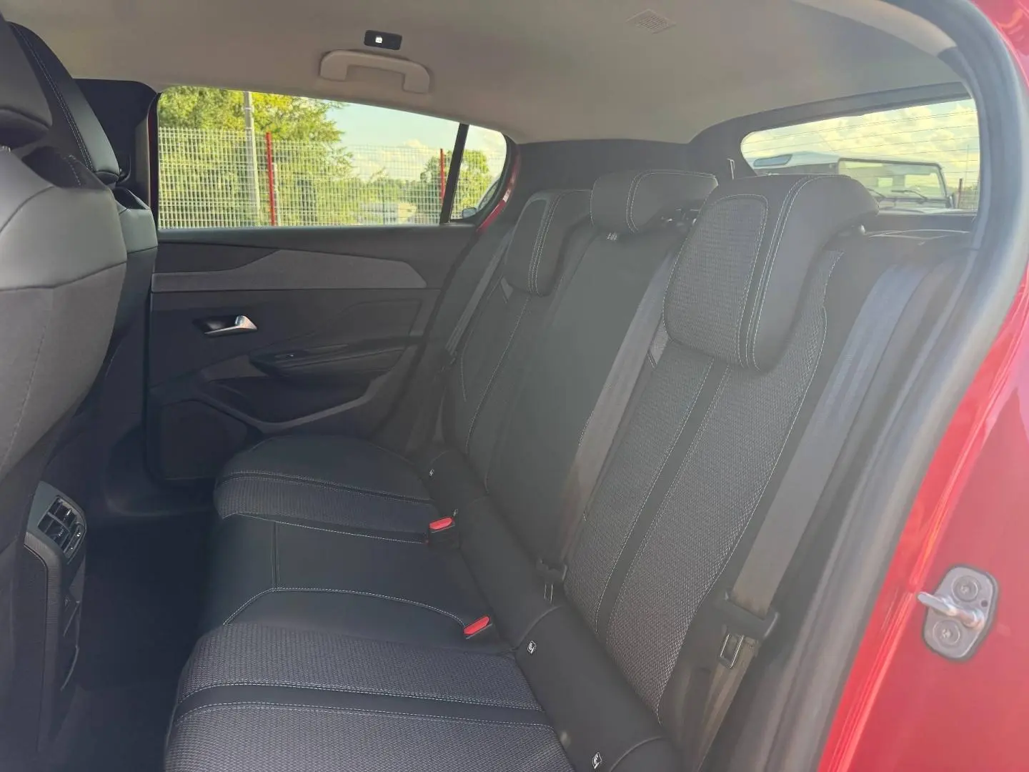 Vue côté droit de la banquette arrière noire avec surpiqûres blanches dans Peugeot 308 rouge Elixir 2025.